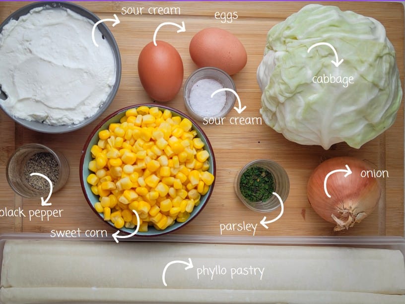 gathering phyllo cabbage pie ingredients: phyllo dough, cabbage, sweet corn, an onion, eggs, sour cream, milk, salt, black pepper