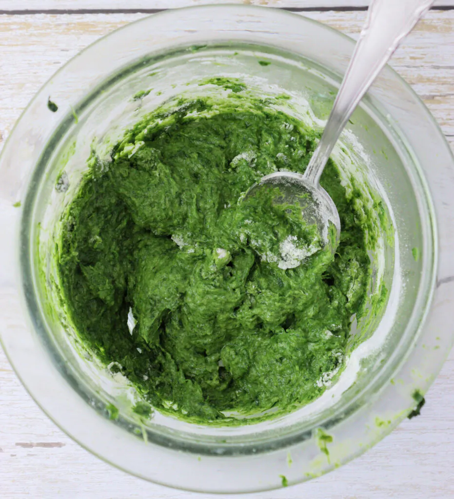 adding flour to the green garlic puree to make the pasta dough