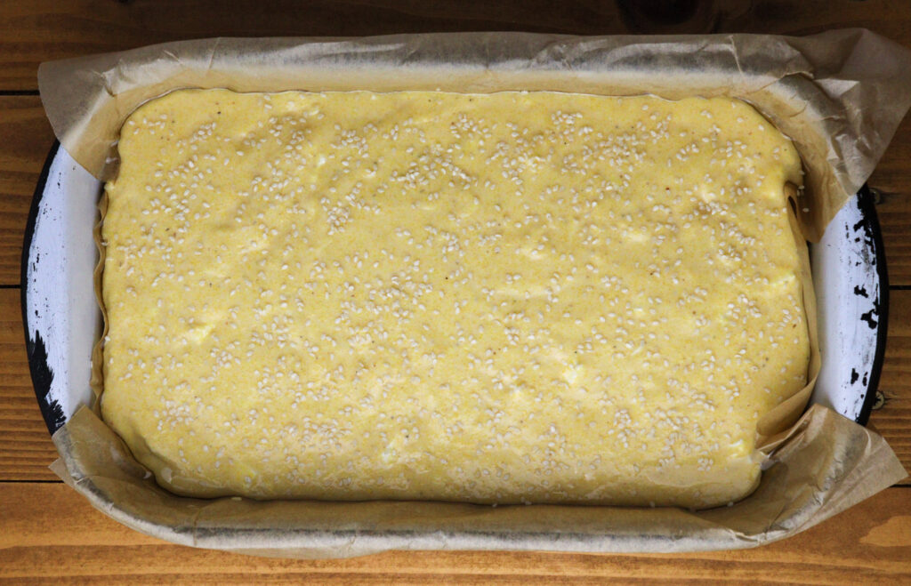 image of polenta bread batter sprinkled with sesame seeds 